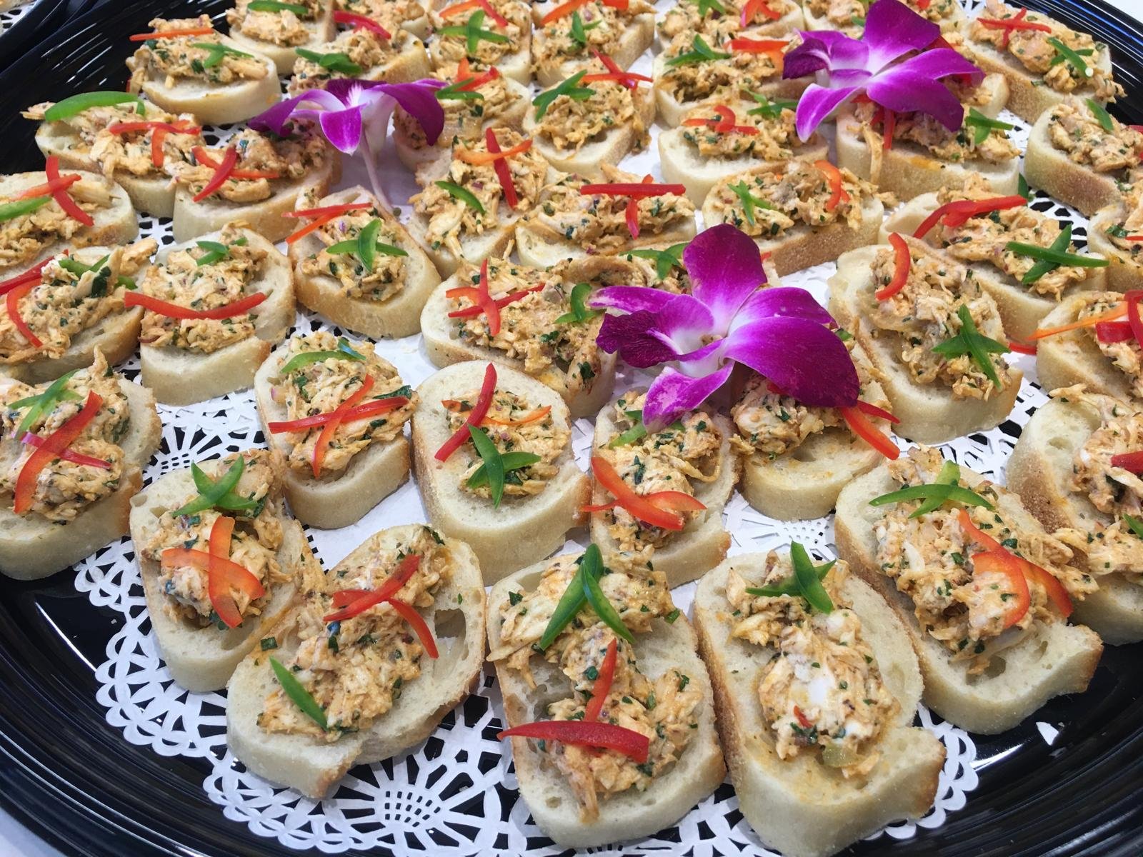 A platter of topped crostini canapés with an orchid.