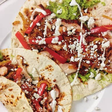 Chicken tacos topped with peppers and crumbled feta.