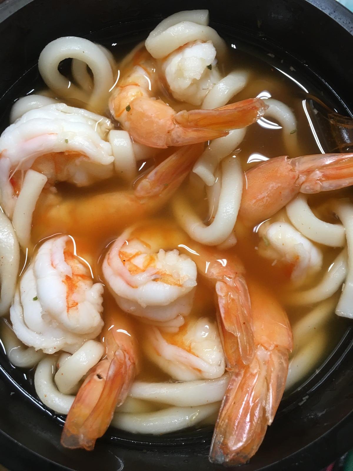 Shrimp and udon noodles in a red broth.